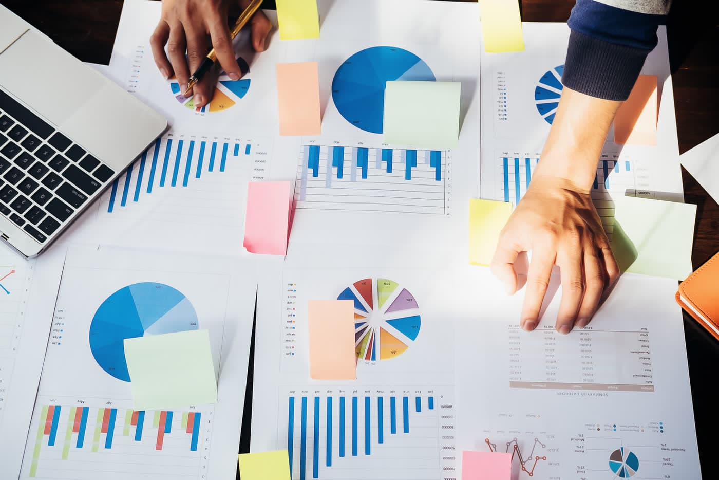 Manos de un equipo trabajando sobre gráficos y notas de planificación